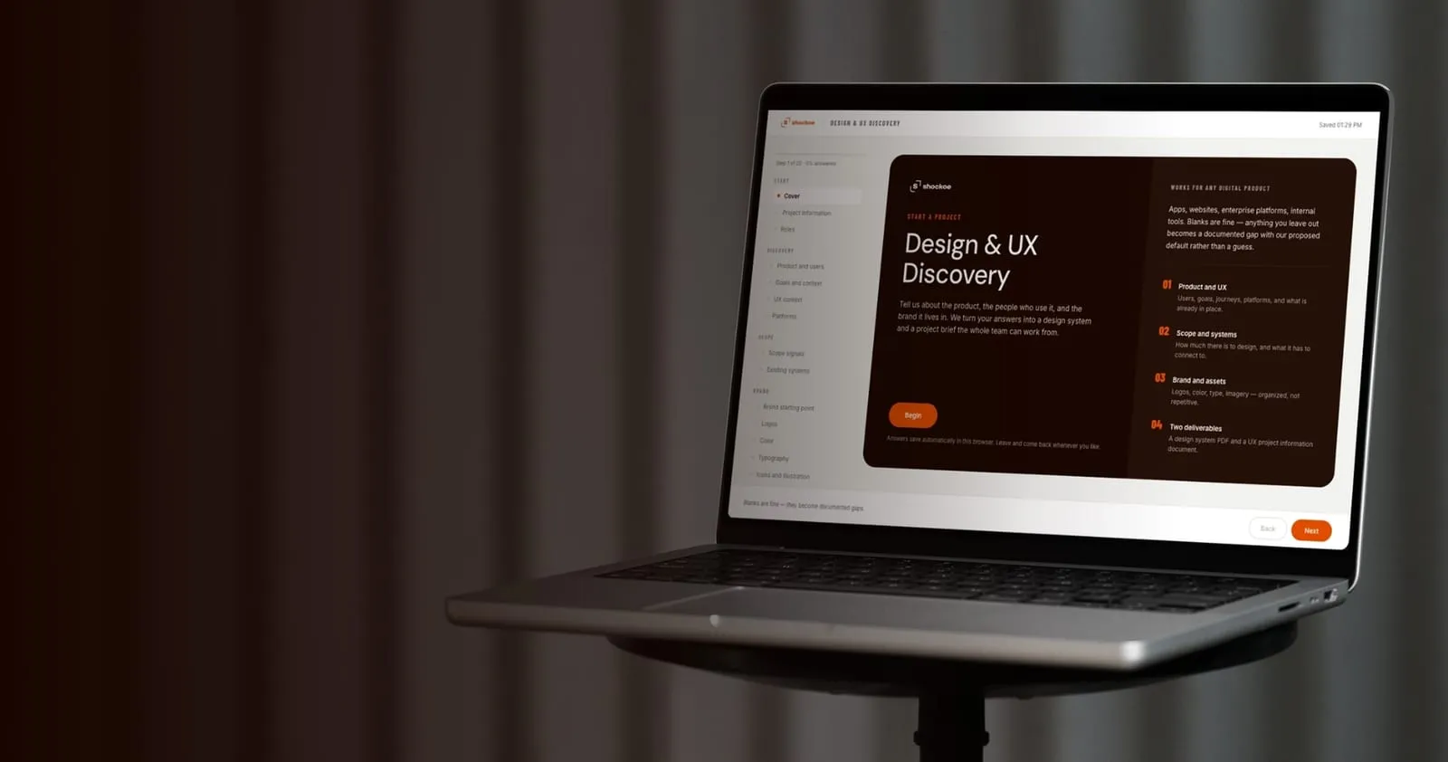 A laptop showing the Shockoe Discovery Wizard, a guided intake that opens with the title Design & UX Discovery and a Begin button.