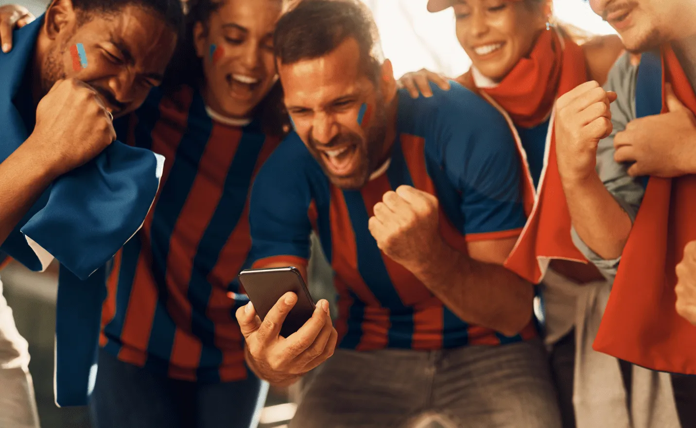 Excited sports fans in team colors cheering as they watch a phone together