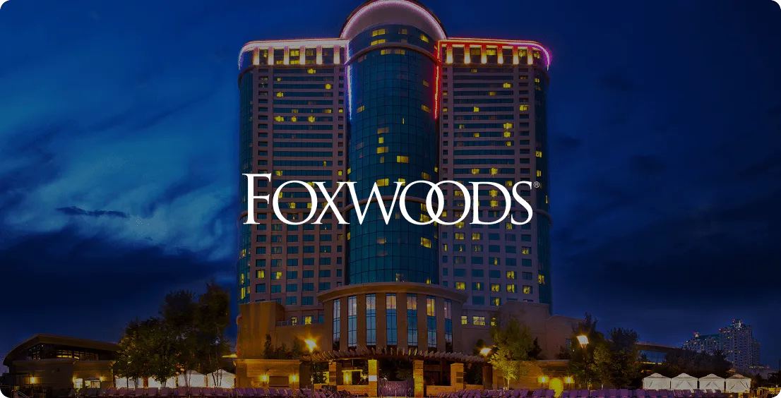 Foxwoods Resort Casino hotel tower against a deep blue evening sky with the Foxwoods logo