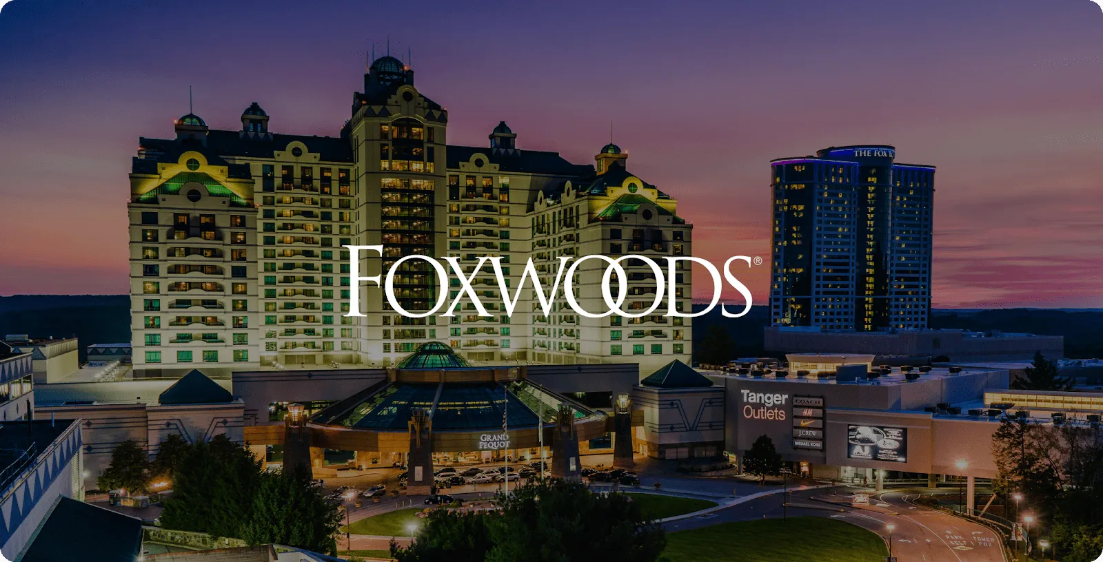 Foxwoods Resort Casino towers lit at dusk with the Foxwoods logo