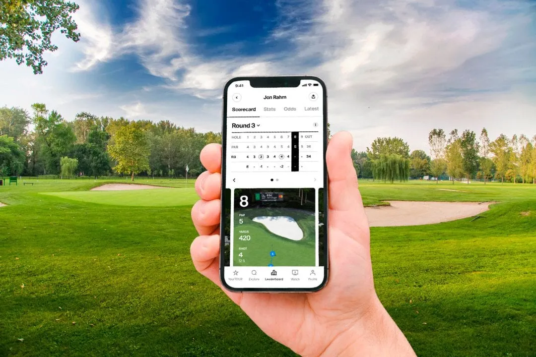 Hand holding a phone showing a golf scorecard and hole map in front of a green fairway