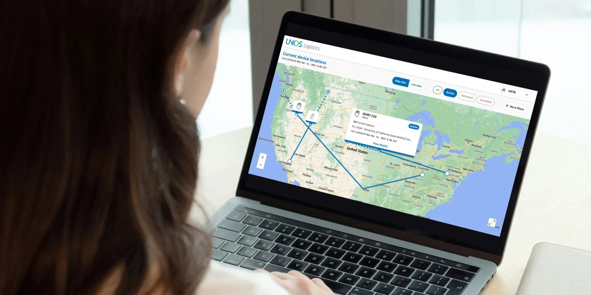 A person viewing a map of the United States on a laptop, with lines showing the routes of organs in transit.