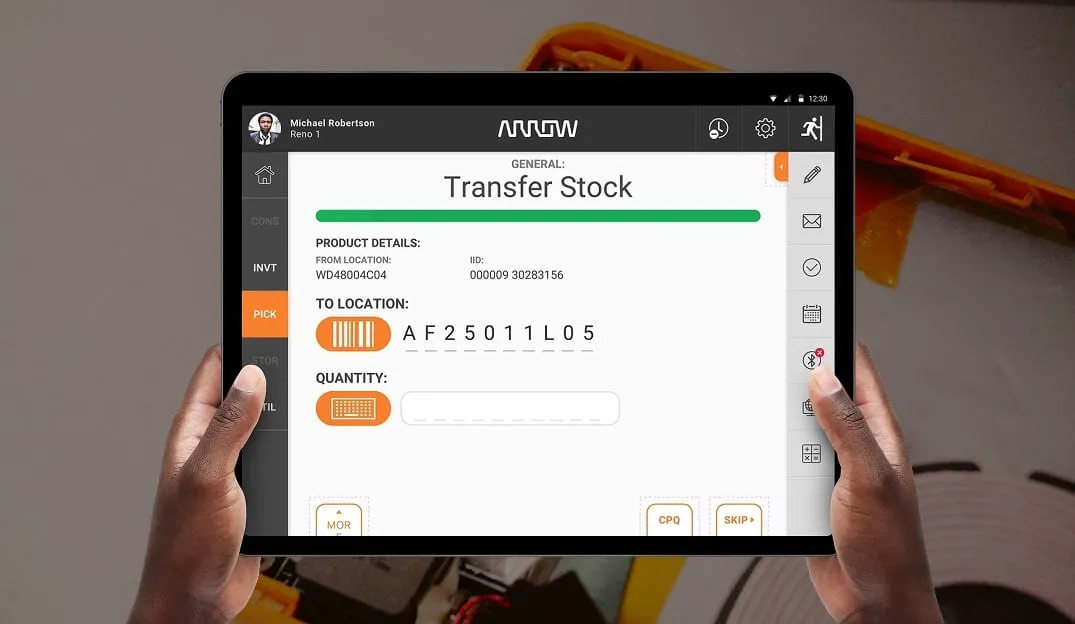 Two hands holding a tablet that shows the Transfer Stock screen of the Arrow warehouse app, with a scan field.