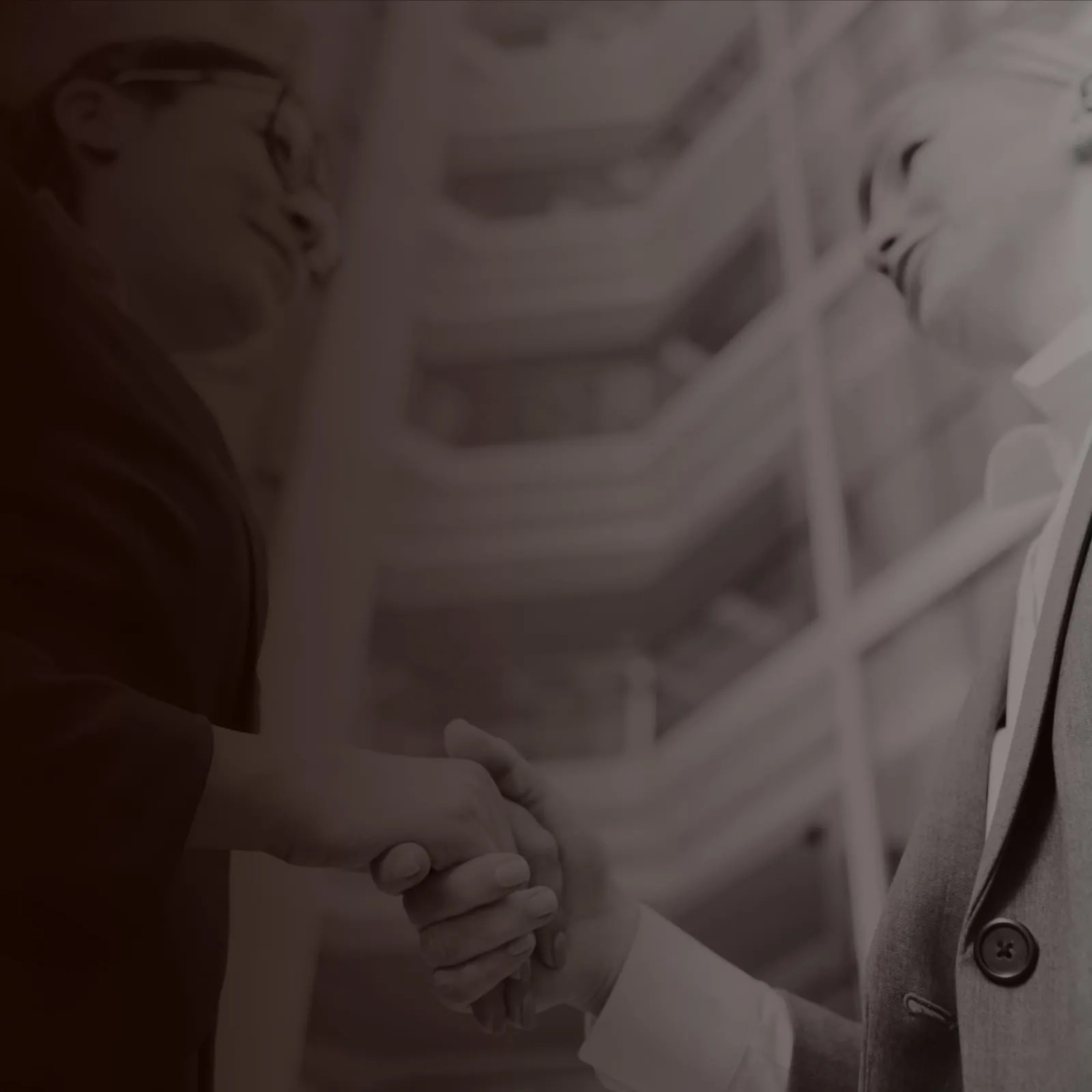 Two business partners smiling as they shake hands.