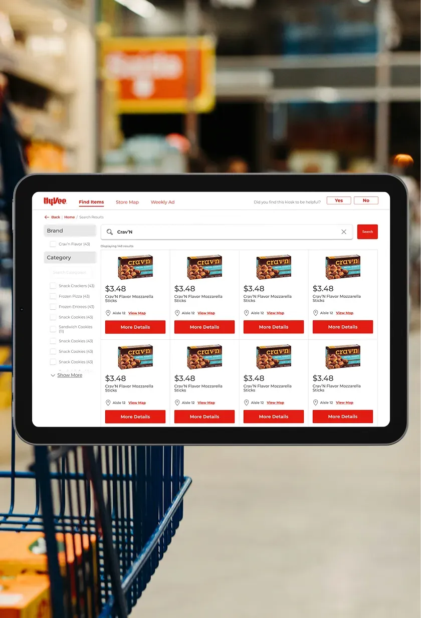 A Hy-Vee kiosk search results screen showing a grid of matching products with prices and More Details buttons.