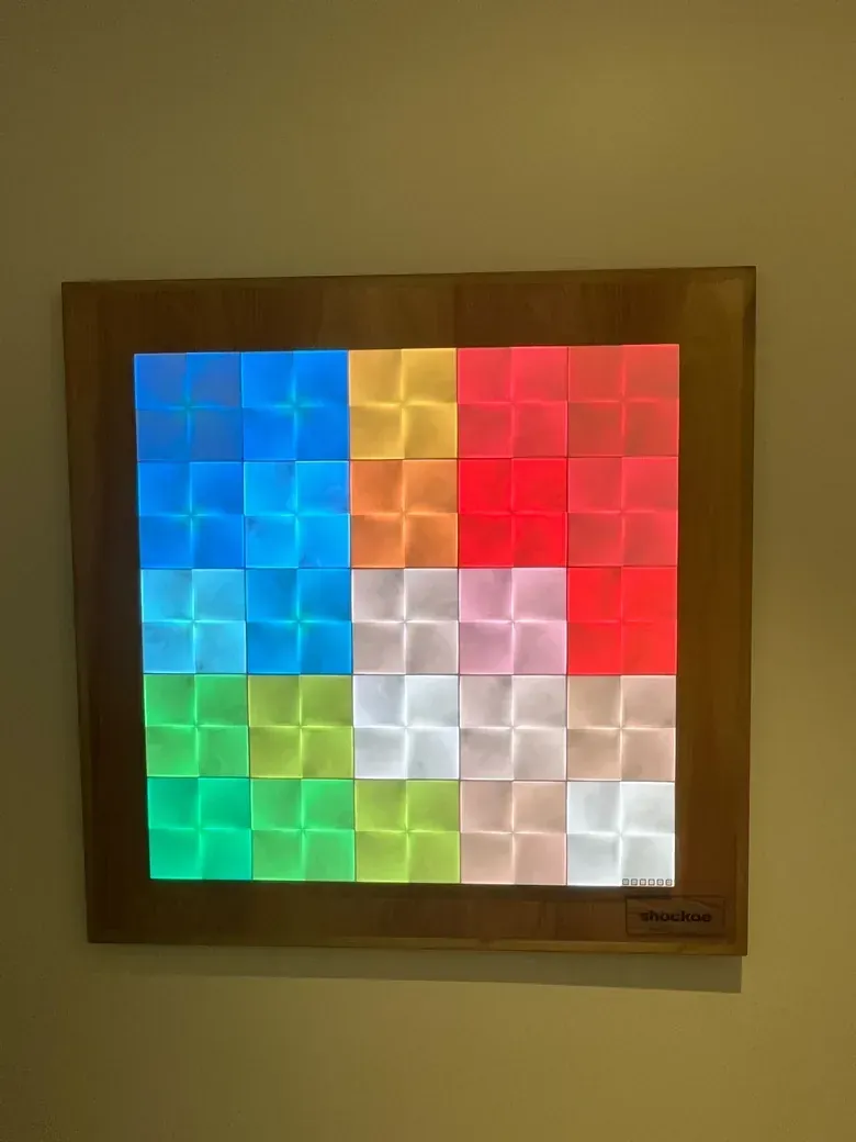 The wall display lit in blue, green, red and white blocks of color in a wooden frame.