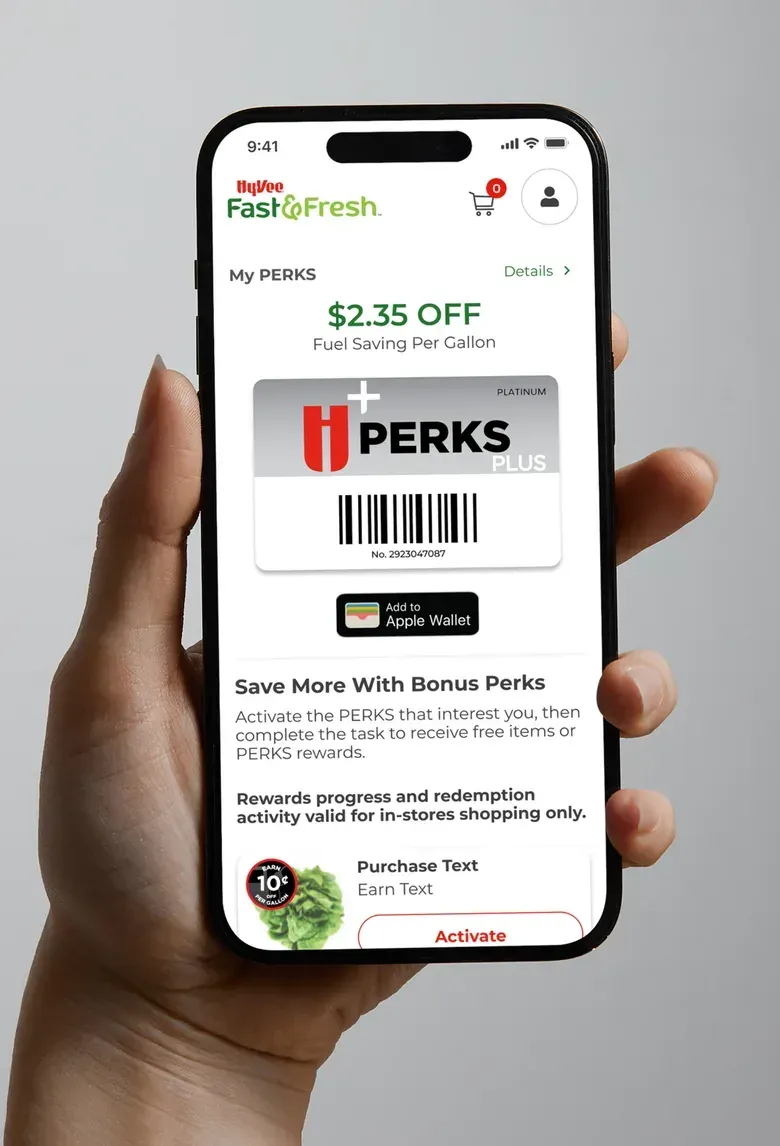A hand holding a phone showing the Fast & Fresh rewards screen with a fuel savings amount, a rewards card and a barcode.