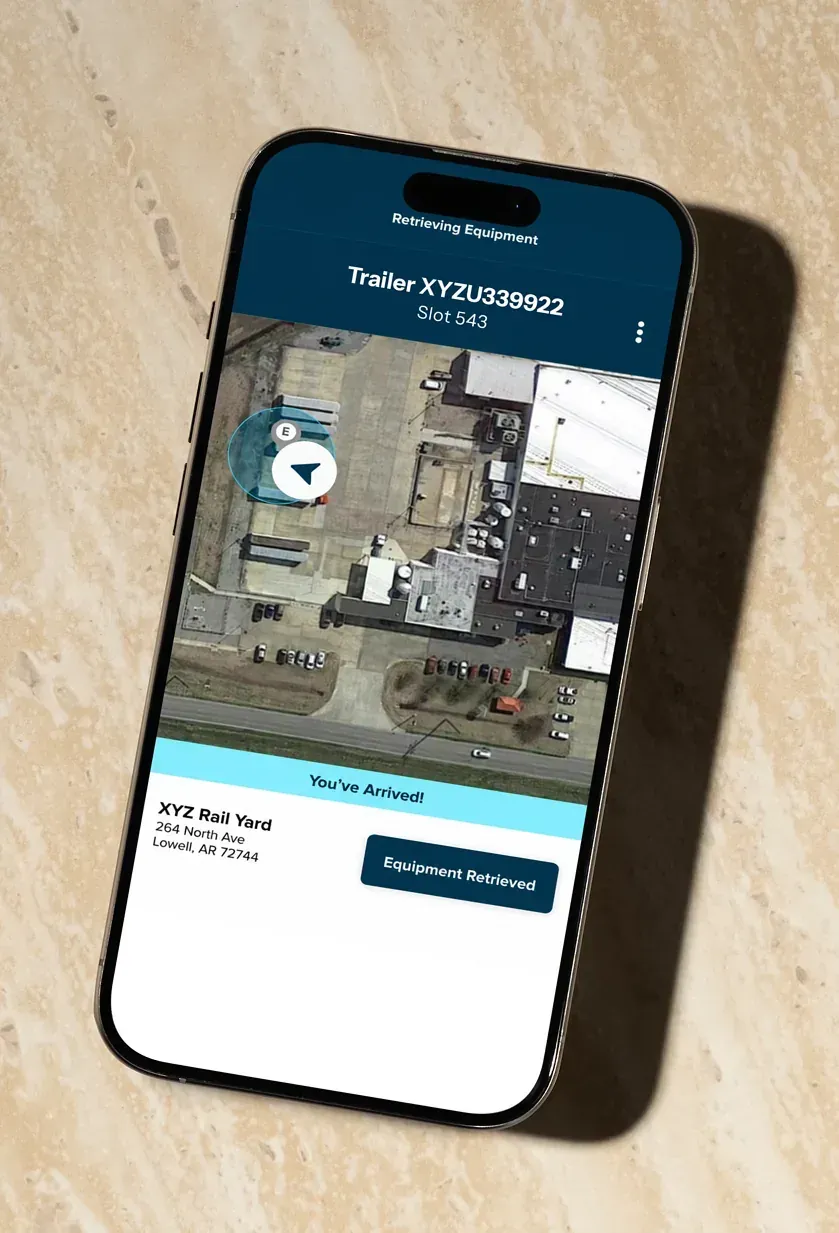 The driver app on a phone showing an arrival at a rail yard, with a satellite map and an Equipment Retrieved button.