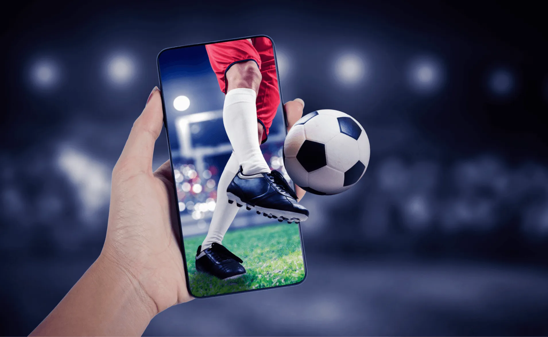 Hand holding a phone from which a soccer player and ball seem to burst out of the screen in a stadium