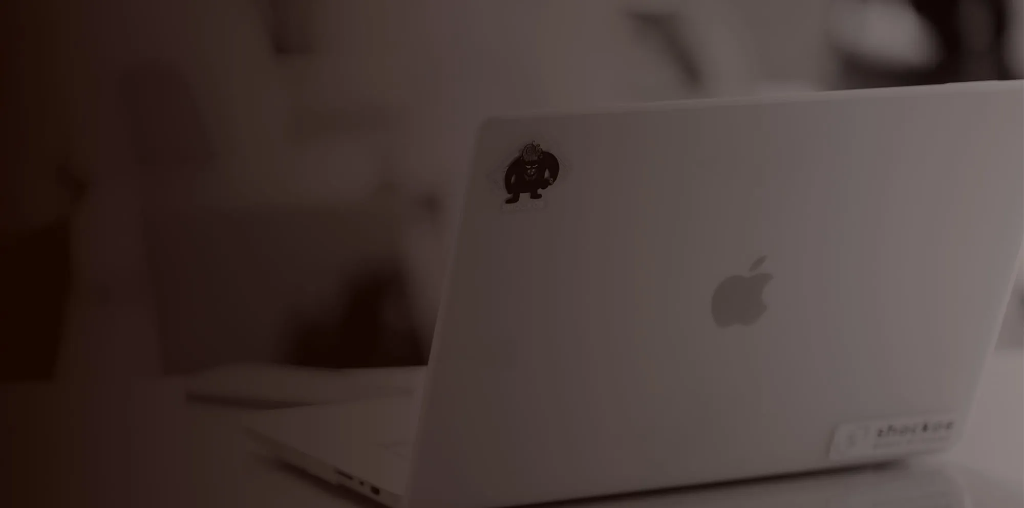A laptop open on a desk, seen from behind, with a Shockoe sticker on its lid.